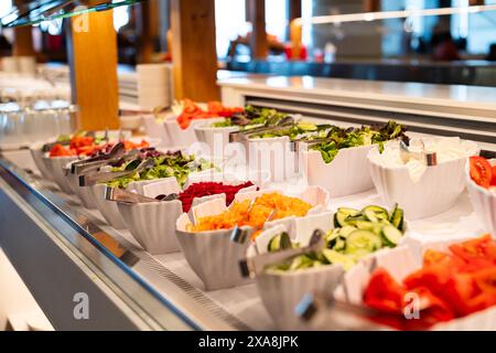 A salad bar with many different types of vegetables and fruits. The salad bar is full of fresh produce and is ready for customers to serve themselves Stock Photo