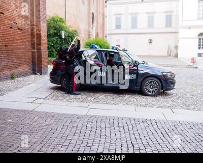 Cremona, Italy - May 27th 2024 Two members of the carabinieri, italy's national military police, are exiting their patrol car in a courtyard, prepared Stock Photo