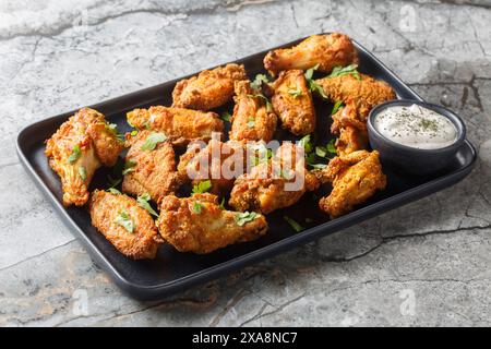 Spicy crispy baked chicken wings breaded with curry close-up in a plate on the table. Horizontal Stock Photo