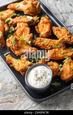 Crispy Curry Chicken Wings served with greek yogurt closeup on the plate on the marble table. Vertical Stock Photo
