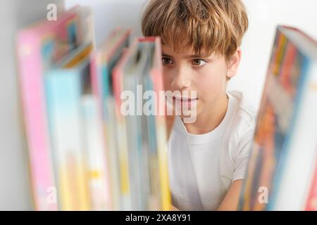 Boy choosing books on shelf. Teenager selecting literature for reading. Books on shelves in bookstore. Learning from books. Stock Photo