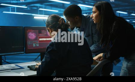 Multiethnic programmer team in server farm workspace surprised by data threatened by hacking attack on computers. Diverse colleagues scrambling to protect data center from unauthorized access Stock Photo