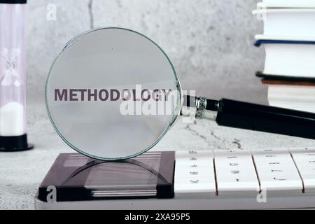 Study or activity concept. The word methodology written through a magnifying glass on a gray background. Black and white image Stock Photo