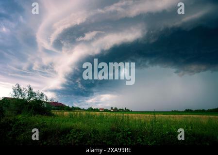 Beautiful and Amazing Ominous Supercell Thunderstorm Clouds over Green Fields in Summer Stock Photo