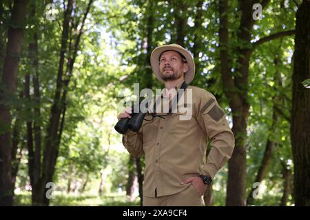 Forester with binoculars examining plants in forest Stock Photo