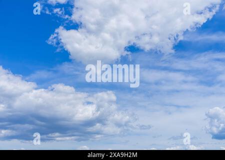 A wide shot capturing fluffy white cumulus clouds floating against a bright blue sky. Stock Photo