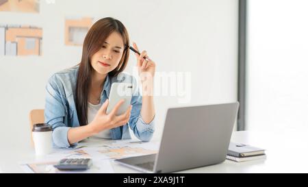 Construction design concept, Female architect using smartphone during thoughtful about house plan. Stock Photo
