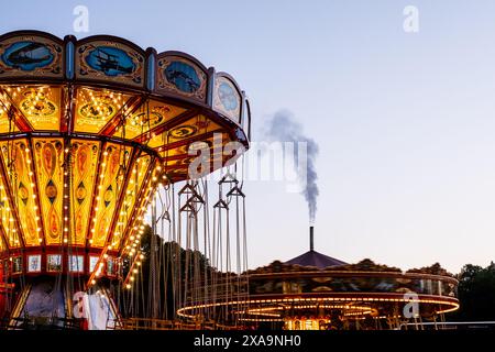 Amusement rides lit up against a cloudy night sky for passengers Stock Photo