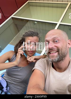 A couple taking a selfie on a bench with their cellphones Stock Photo