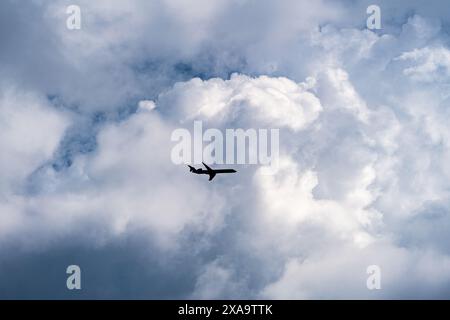 A small airplane flying amidst large clouds in a blue sky Stock Photo