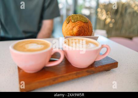 Two pink coffee cups and a croissant on a table Stock Photo
