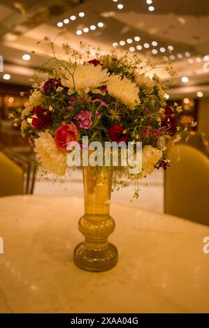 Various flowers in a vase on a table indoors Stock Photo