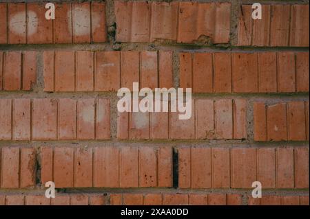 A weathered red brick wall with faded paint Stock Photo