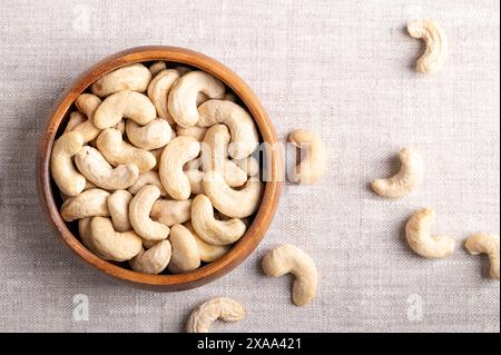 Cashew nuts, raw cashews in a wooden bowl on linen fabric. Seeds of shelled fruits of cashew tree Anacardium occidentale. Used as snack nuts etc. Stock Photo