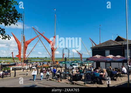 People outside Fish On The Quay pub by sailing barges moored at Hythe Quay, Maldon, Essex, on the River Blackwater, River Chelmer. Riverside pub Stock Photo