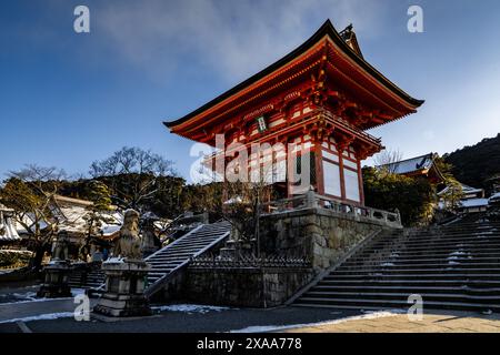 Early morning view of rare snow covered Kiyomizudera Buddhist Temple with ancient bright orange pagodas, statues, gates, and a temple complex in Kyoto Stock Photo