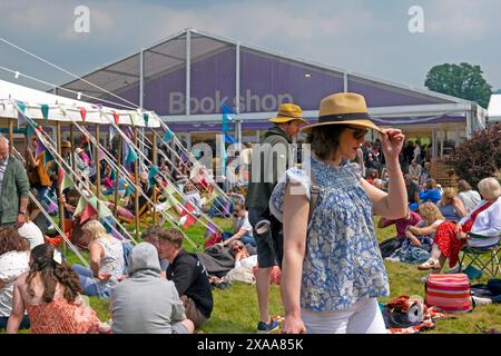 Fashion young woman holding straw hat wearing sunglasses outside book shop on Hay Festival 2024 site Hay-on-Wye Wales UK Great Britain  KATHY DEWITT Stock Photo