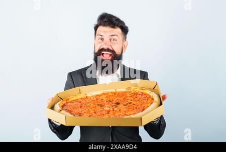 Pizza delivery. Food, business lunch. Businessman holding cardboard box with pizza. Fast food. Tasty italian snack. Happy bearded man in suit with del Stock Photo