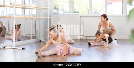 During workout, girls sit on floor and do splits. Stock Photo