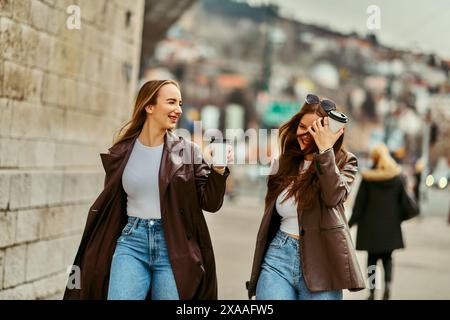 Two beautiful business women go to work while holding cups of coffee in their hands Stock Photo