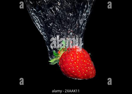 strawberry splashing into water on black background, underwater shot Stock Photo
