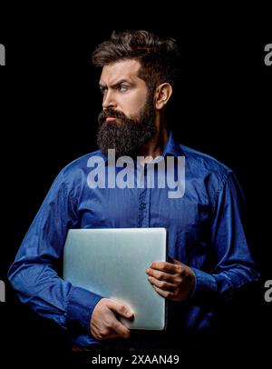 Bearded male businessman holding a computer in his hands isolated on black background. Confident business expert Stock Photo