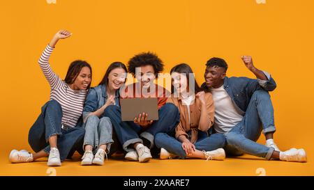 International Group of Friends Celebrate Success With Laptop on Yellow Stock Photo