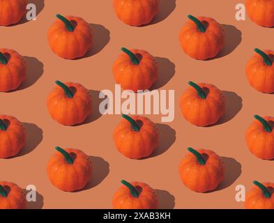 Trendy autumn or fall pattern made with orange pumpkins on orange background. Minimal autumn composition. Nature flat lay. Season concept. Stock Photo