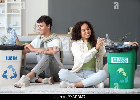 Young couple with garbage containers sorting rubbish at home. Recycling concept Stock Photo