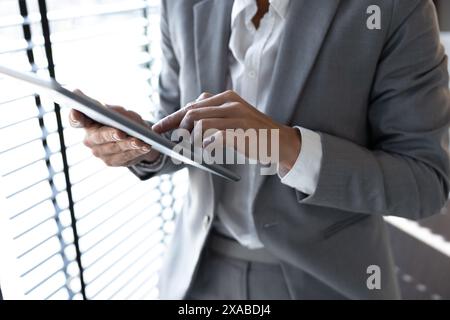 Professional businesswoman working on tablet checking emails while standing Stock Photo