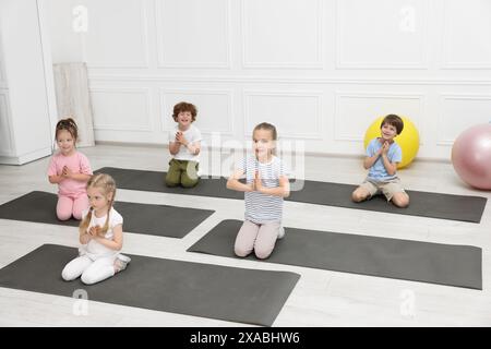 Group of children doing gymnastic exercises on mats indoors Stock Photo