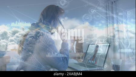 Image of network of connections with icons over clouds and woman using laptop Stock Photo