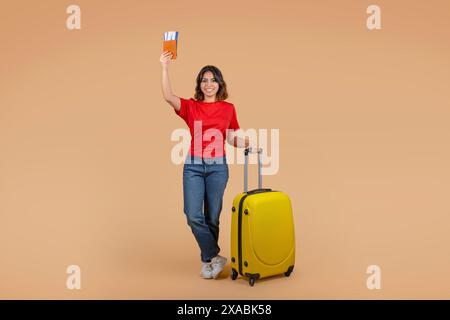 Young Woman Holding Passport and Tickets While Standing With Suitcase Stock Photo