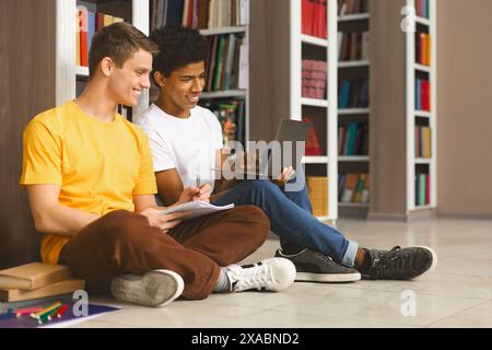 Two young guys studying on floor in library Stock Photo