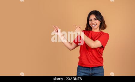 Young Woman Points to Left and Right Against Tan Background Stock Photo