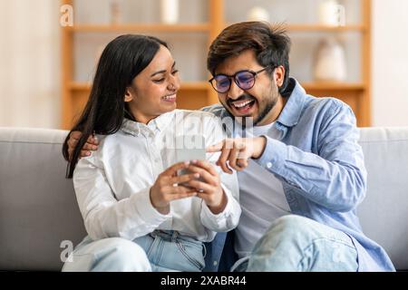 Man and Woman Sitting on Couch Looking at Cell Phone Stock Photo
