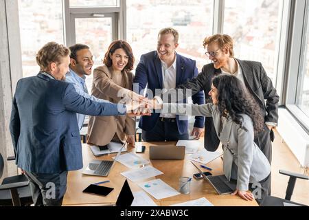 Business Team Celebrating Success With Hand Stack in Modern Office Stock Photo