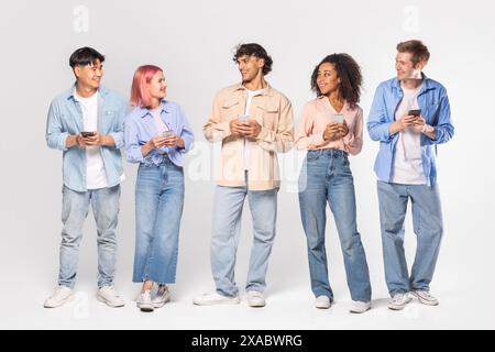Multiracial Group of Young Adults Using Smartphones Against White Background Stock Photo