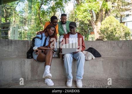 Group of enthusiastic African American student friends work on learning project together outside. Stock Photo