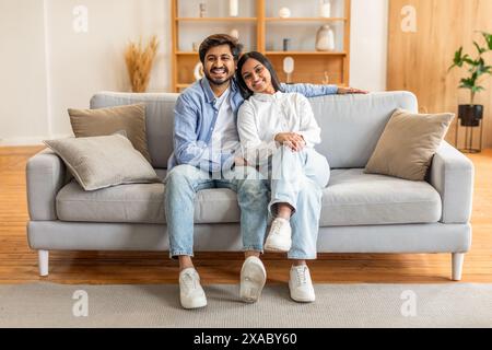 Loving Man and Woman Sitting on Couch in Living Room Stock Photo