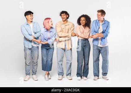 Diverse Group of Friends Holding Hands, Laughing Together in Studio Stock Photo