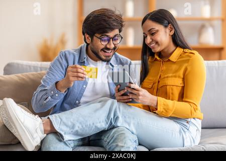 Happy Couple Shopping Online in Living Room on Relaxed Evening Stock Photo