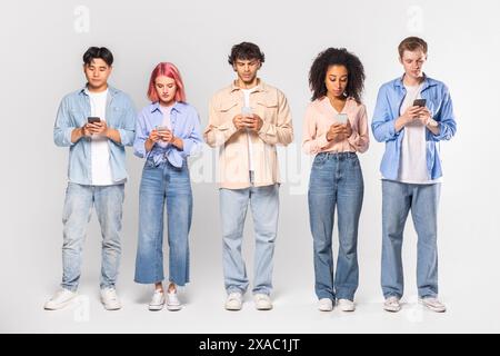 Five Diverse Young Adults Using Smartphones Against White Background Stock Photo