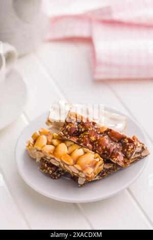 Close Up of almond Brittle Bars With Caramelized Coating on plate on a white table. Stock Photo