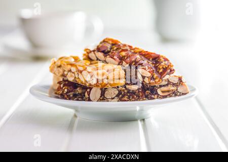Close Up of almond Brittle Bars With Caramelized Coating on plate on a white table. Stock Photo
