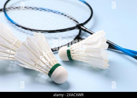 Feather badminton shuttlecocks and rackets on light blue background, closeup Stock Photo