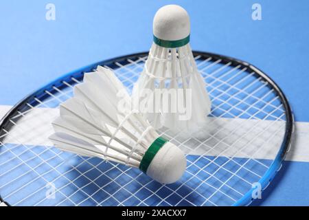 Feather badminton shuttlecocks and racket on blue background, closeup Stock Photo