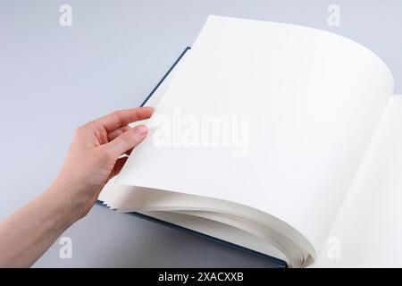 Woman with open photo album at light table, closeup. Space for text Stock Photo