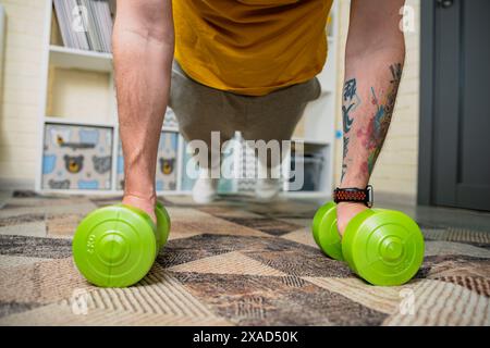 Man Doing Push Ups With Dumbbells At Home Stock Photo