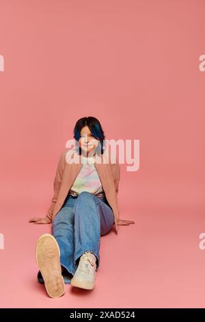 An Asian teenage girl sit on the ground with crossed legs, exuding serenity and warmth in a studio setting. Stock Photo